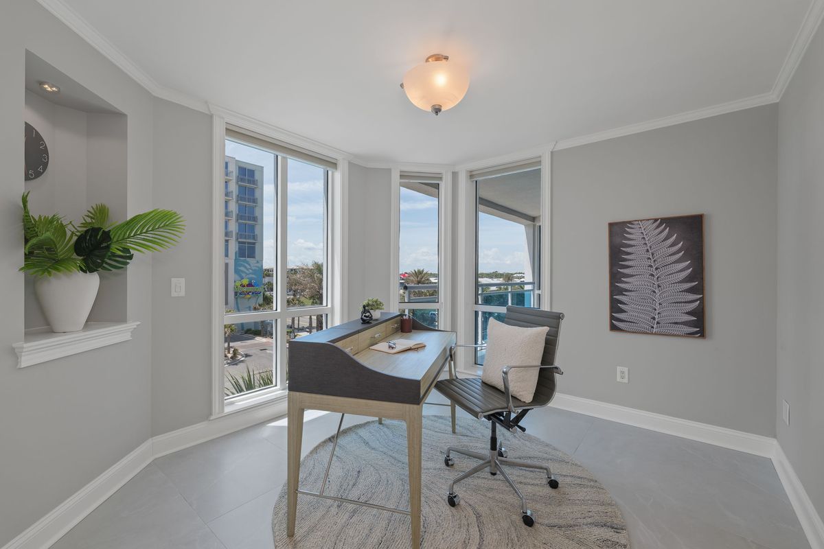 Corner office with a writing desk, a desk chair, a round rug and tall windows